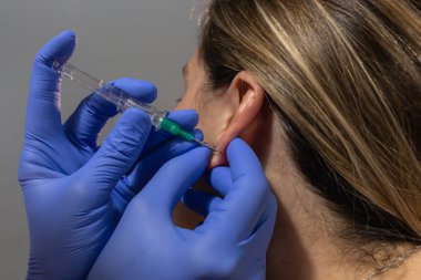 Sarışın bir kızın kulağını deldirirken.