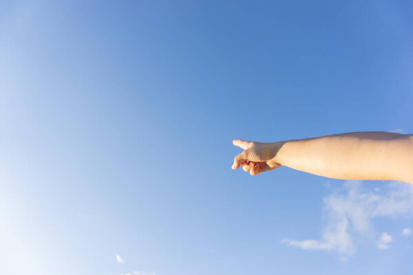Arm pointing to clear blue sky