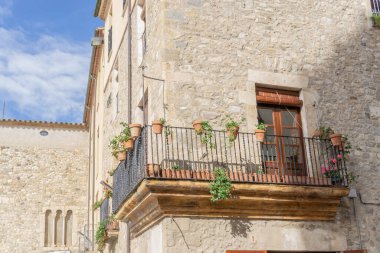 GIRONA, SPAIN - 11 Ekim 2020: Besalu kasabasında eski bir evin balkon resmi, tırabzanda saksılar ve ahşap panjurlar