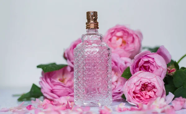 女性香水和粉红色的花朵 — 图库照片