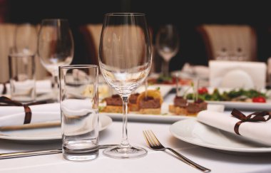 Festival sofra gözlüklü bir tablo. Boş gözlük stand yakın tabak ve çatal ile beyaz tablewear süslenmiş ziyafet masada