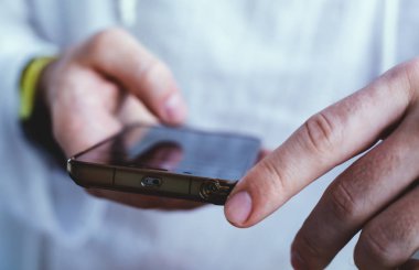 Eller cep telefonu tutuyor. Cep telefonu tutan adam.