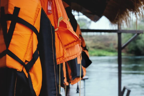 Gilets de sauvetage nautiques suspendus sur rack sur jetée — Photo
