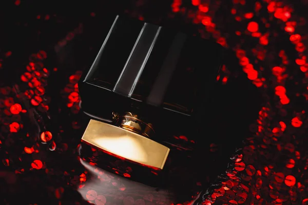 Perfume negro sobre fondo rojo oscuro —  Fotos de Stock