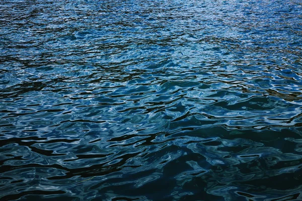 Suavemente ondas de lapeado forman ondas en la superficie de wa azul oscuro —  Fotos de Stock