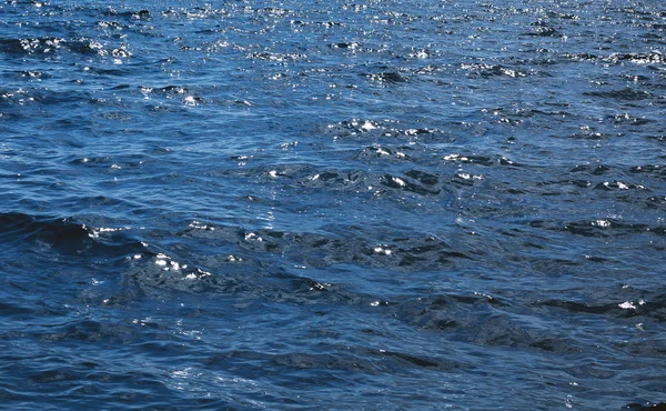 Leicht plätschernde Wellen bilden Wellen auf der Oberfläche dunkelblauen Wassers. — Stockfoto