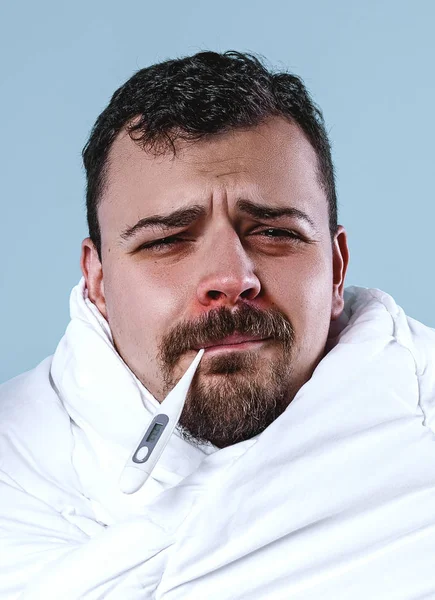 Człowiek z zimną siedząc na kanapie z termometrem w usta — Zdjęcie stockowe