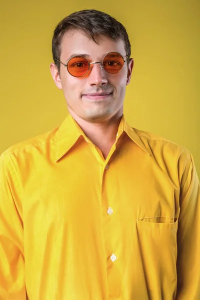 Portrait of young man in sunglasses posing on yellow background. — Stock Photo, Image