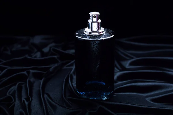 black perfume on a black fabric background