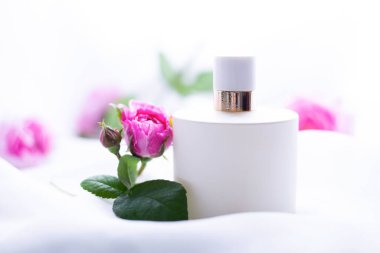 Arka planda çiçekler olan parfüm şişesi.