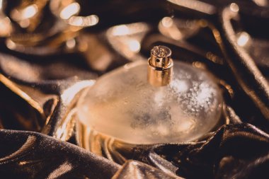 Soyut altın arka planda bir şişe parfüm.