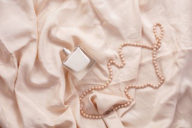 Kadın parfümü şişesi ve pembe ipekli inciler..