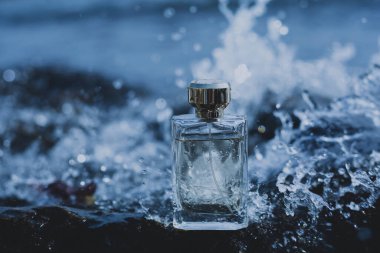 Mavi su arka planında parfüm şişesi