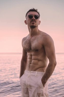 Denize karşı çıplak gövdeli yakışıklı bir adam.