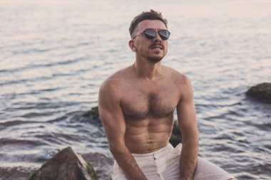 Yakışıklı adam deniz kenarında gün batımını seviyor.