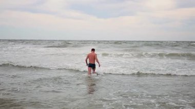 Genç bir adam denizde yüzmekten hoşlanır.