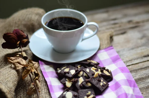Ahşap arka planda bir fincan kahve ve lezzetli kurabiyeler. Çay saati ve kahvaltı konsepti.