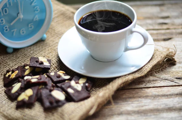 Ahşap arka planda bir fincan kahve ve lezzetli kurabiyeler. Çay saati ve kahvaltı konsepti.