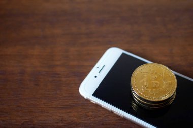 Fiziksel Bitcoins yığını ile smartphone sanal para kavramı ahşap arka plan üzerinde