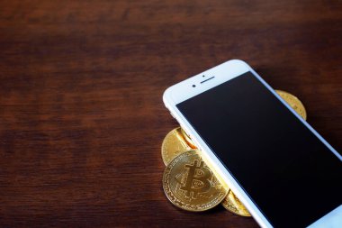 Fiziksel Bitcoins yığını ile smartphone sanal para kavramı ahşap arka plan üzerinde