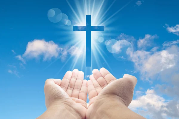 태양 위에 떠있는 빛나는 흰색 십자가로 가득 찬 손 — 스톡 사진