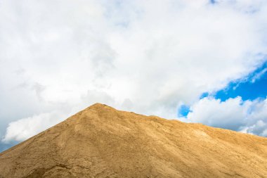 Sarı kum, bulutlu gökyüzü güneş tarafından aydınlatılmış büyük bir dağ.
