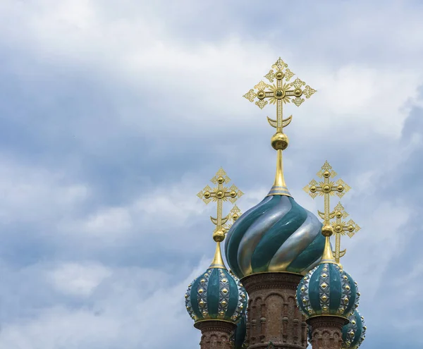 Beautiful church domes with gold crosses against a cloudy sky on a cloudy day.