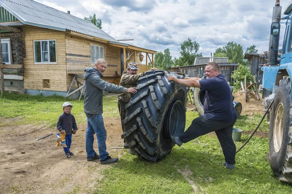 Yaroslavl bölgesi, Rusya Federasyonu - 06/11/2018: üç adamları topla büyük bir tekerlek bir traktöre 11 Haziran 2018, Yaroslavl bölgesi, Rusya Federasyonu. 