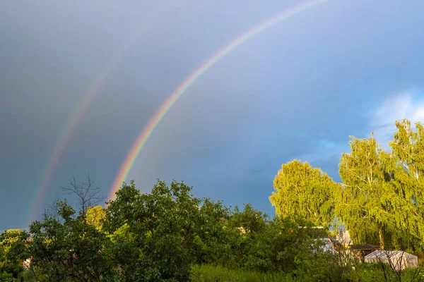 Multicolor rainbow against the dark cloudy sky, Russia.