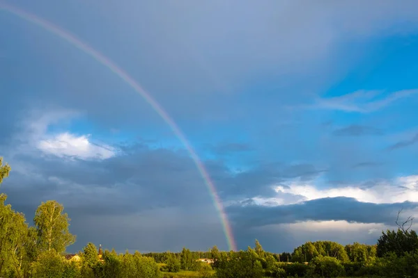 Multicolor rainbow against the dark cloudy sky, Russia.