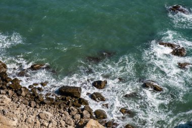 Kayalık bir sahil ve sörf beyaz köpük ile Arka plan. 