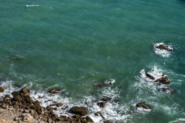 Kayalık bir sahil ve sörf beyaz köpük ile Arka plan. 