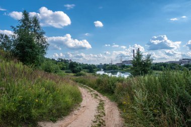 Güneşli bir yaz gününde Uvod nehri boyunca uzanan toprak yol, Ivanovo şehri, Rusya.
