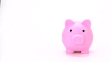 Elin önü, ünvan ya da bitiş kredisi için beyaz arkaplandaki oyuncak bebek bankasına para koyuyor. Vdo 4k, 1080, FHD, full HD. Pembe kumbaraya para kaydet. Metin, kopyalama veya grafik için boş alanı olan izole et.