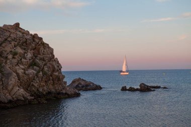 Gün doğumu sırasında Costa Brava koyunda küçük tekne