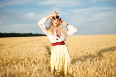 Buğday tarlasında beyaz bir elbise giymiş uzun sarı saçlı genç beyaz bir kadın.