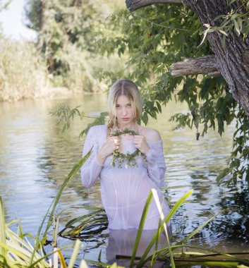 Yazın ormanda nehirde uzun sarı saçlı genç beyaz bir kadın.