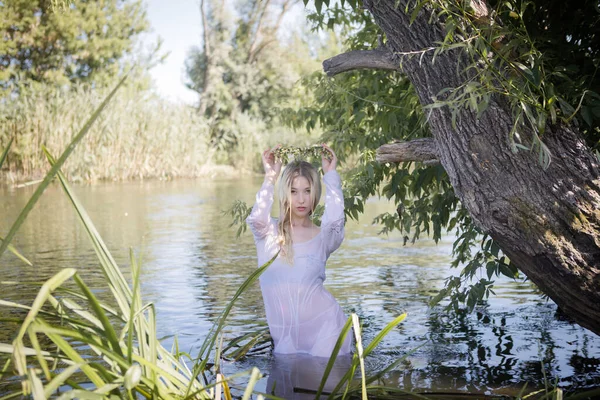 Yazın ormanda nehirde uzun sarı saçlı genç beyaz bir kadın.