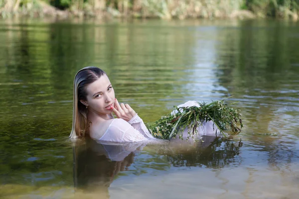 Yazın ormanda nehirde uzun sarı saçlı genç beyaz bir kadın.