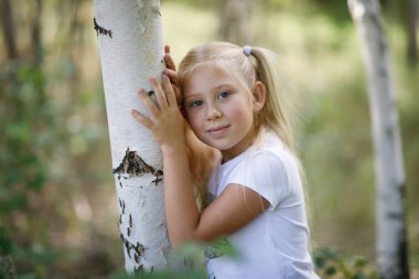 huş ağacında uzun sarı saçlı tatlı beyaz kız.