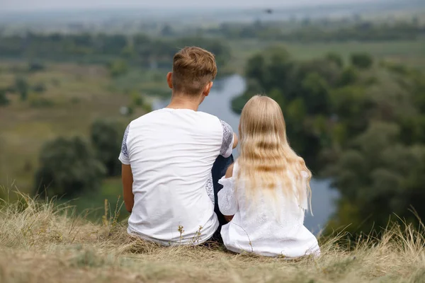 男の子と女の子は川の上の丘の上に座っている — ストック写真