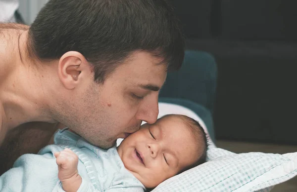 Şefkatli bir baba bebeği kucağına alır ve öper. Evde mutlu bir aile.