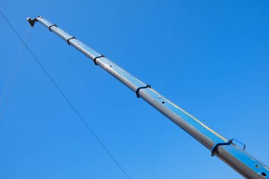 Teleskopik vinç açık mavi gökyüzüne karşı kablolarla patladı. Endüstriyel inşaat ekipmanları, kaldırma ve inşa için ağır makineler.
