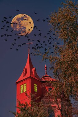 Gece gökyüzünün altında kırmızı ışıklı bir kule, büyük bir dolunay ve tepemizde uçuşan bir sürü siyah kuşun olduğu karanlık, ürkütücü bir sahne. Atmosfer gizemli ve rahatsız edici..