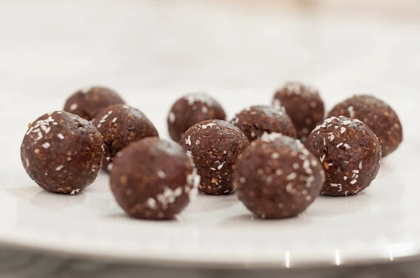 many handmade chocolate bon bons covered with coconut flake. chocolate truffles on a white plate.