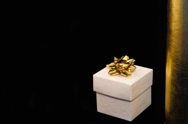 Siyah ve altın zemin üzerine altın süslemeli tek bir hediye kutusu..