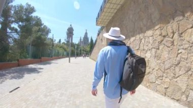 Sırt çantası ile bir kap içinde genç bir adam üzerinde Mount Tibidabo Barselona, İspanya, Sacred Heart tapınağa gider sonra dönüyor ve gülüyor