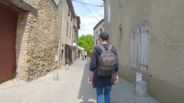 Carcassonne Fransa eski sokaklar boyunca sırt çantası ile bir kap içinde genç bir adam gider, sonra o döndü ve gülümsüyor