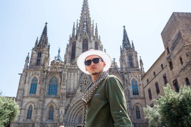 Genç bir adam, bir turist bardaklarda ve The Cathedral Holy Cross ve Aziz Eulalia Barcelona, İspanya'nın önünde bir şapka