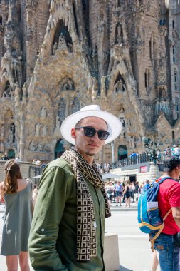Yazı işleri. Mayıs 2018. Yaz aylarında cephe Sagrada Familia. Genç bir adam, bir turist güneş gözlüğü ve şapka Sagrada Familia için Barselona, İspanya'nın önünde